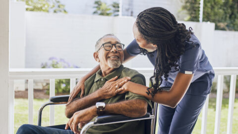 Young female nurse hugging an elderly man in a wheelchair
